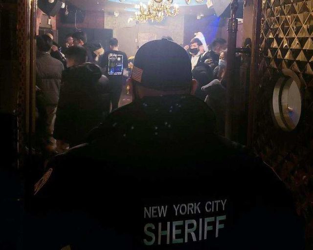 A member of the New York City Sheriff's Office looks at partygoers at a New Year's Eve party in Queens.